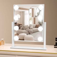 a mirror sitting on top of a white dresser next to a table with a lamp