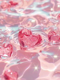 three pink hearts floating in water with bubbles