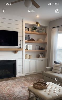 the living room is decorated in white and has built - in shelvings, a fireplace, and a flat screen tv