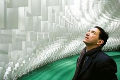 a man standing in front of a wall made out of white plastic cups and tubes