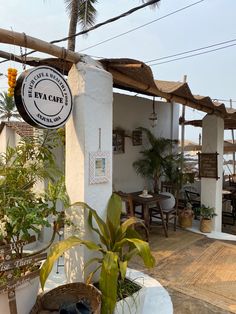 the outside of a restaurant with tables and chairs on the patio, next to palm trees