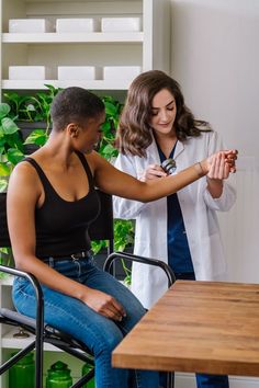 a woman sitting in a chair next to a doctor who is holding her hand out