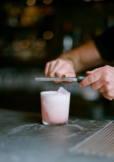 a person holding a knife over a drink