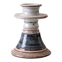 a white and brown vase sitting on top of a table