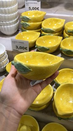 a hand holding a yellow bowl in front of rows of white bowls