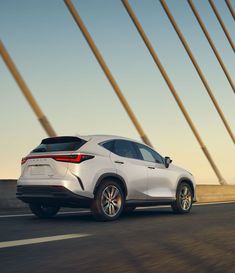 the rear end of a white toyota suv driving down a road with tall poles in the background