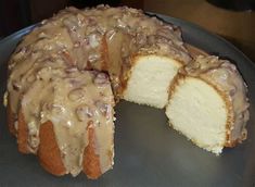 a bundt cake covered in frosting on top of a metal pan with one slice cut out