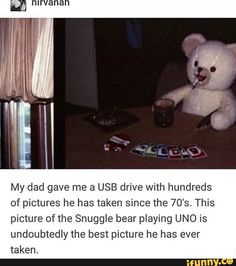 a white teddy bear sitting on top of a table next to a cup and playing uno