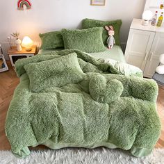 a bed covered in green fluffy blankets and pillows