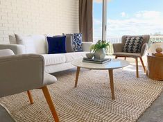 a living room filled with furniture and a large window overlooking the ocean on a sunny day