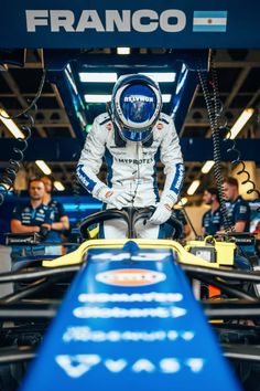 a man sitting on top of a race car in front of other men behind him