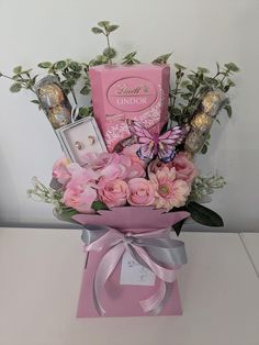 a bouquet of flowers and chocolates in a pink gift box with a butterfly on it