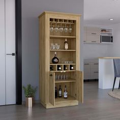 a wooden cabinet filled with lots of bottles and glasses next to a dining room table