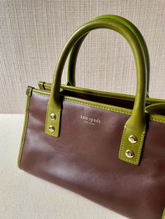 Vintage 90s original Kate Spade New York handbag. Chocolate brown with avocado green top handle and trim are in true vintage style.  Superior leather quality. Polka dot lining for added charm. * All leather outer * cotton interior * inside zip pocket * top zip closure * 10.5" x 6.5" x 6" * handle drop 4.5" Excellent vintage condition. Minimal wear on leather. Small spotting on interior lining. Green Leather Handbag, Vintage Kate Spade, Top Handle Bags, Brown Leather Bag, Avocado Green, Green Top, Pocket Top, Kate Spade Bag, Green Leather