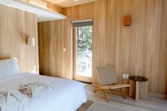 a white bed sitting in a bedroom next to a wooden paneled wall and window