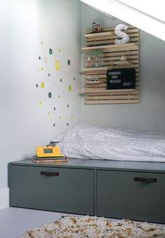 a bed with two drawers underneath it and a wall hanging on the wall next to it