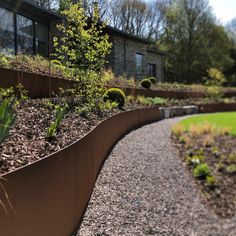 a garden with gravel and plants in front of a house on the side of a road