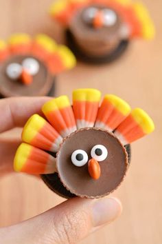 a hand holding a cupcake decorated to look like a turkey