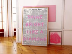 a pink and white poster sitting on top of a wooden floor next to a window