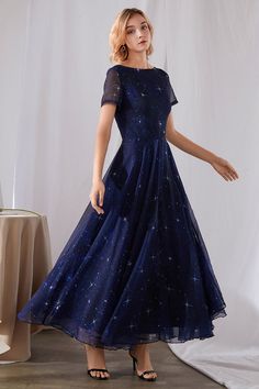 a woman in a blue dress standing next to a white backdrop with stars on it