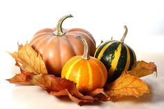 two pumpkins and some leaves on a table