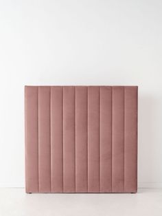 a pink velvet headboard against a white wall