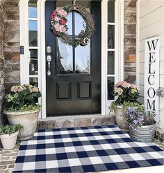 the front door is decorated with potted flowers and a welcome mat that says welcome