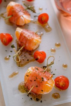 small appetizers with tomatoes and other vegetables on a white platter next to wine glasses