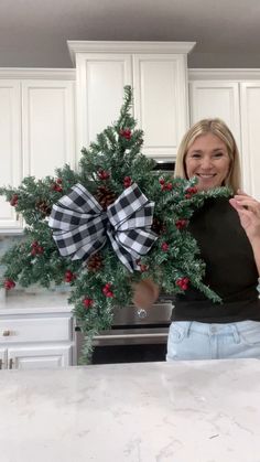 a woman holding a christmas wreath in her kitchen