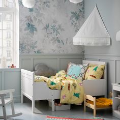 a child's bedroom with floral wallpaper and white furniture