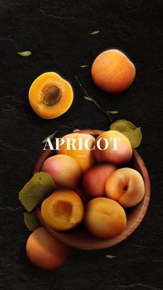 apricots in a wooden bowl on a black surface with leaves and fruit next to it