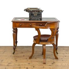 an old fashioned desk with a typewriter on it and a leather chair in front