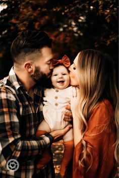 a man and woman holding a baby in their arms