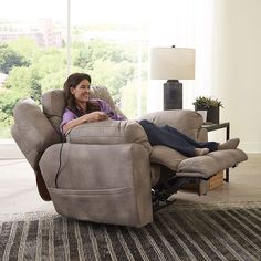 a woman sitting in a recliner with her feet up on the armrests