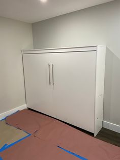 a white cabinet sitting in the corner of a room with some blue tape on it