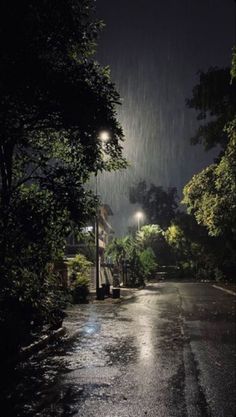 an empty street at night with the lights on and rain coming down from the sky