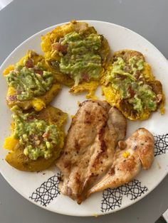 a white plate topped with meat and veggies covered in guacamole