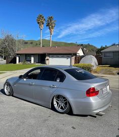 a silver car parked in front of a house with palm trees on the other side