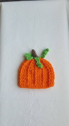 an orange knitted pumpkin sitting on top of a white table cloth covered in crochet