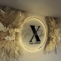 a lighted sign that says the lodge with feathers around it and an x on top