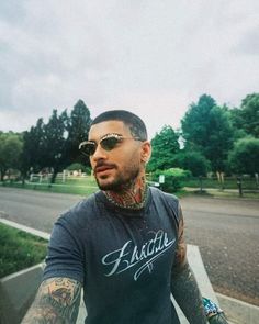 a man with tattoos and piercings on his arm is riding a skateboard down the street