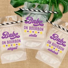 three bags with the words babe on bourbon are next to a plant and some paper straws