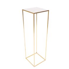 a gold metal and glass side table with a white top on an isolated surface, viewed from the front