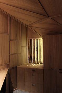 an empty room with wooden walls and cupboards in the corner, light coming through