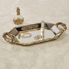 PRICES MAY VARY. This item is our exclusive! Unique mirrored vanity tray Venetian gold finish Scrollwork medallions The Brya Mirrored Vanity Tray exudes a grand grace with classical elements. Finished in marvelous Venetian gold, the resin tray features a faceted shape, a mirrored glass surface, scrollwork medallions, and acanthus leaf handles. Measures 17.5 Wx9 Dx2 H. This item is our exclusive! Unique mirrored vanity tray Venetian gold finish Scrollwork medallions Acanthus leaf handles. Perfume Stand, Dresser Accessories, Mirrored Vanity, Makeup Tray, Sunglasses Organizer, Mirror Vanity Tray, Classical Elements, Mirrored Wall, Vanity Accessories