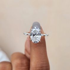 a woman's hand holding an engagement ring with a large diamond in the center