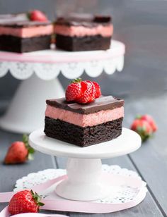 a piece of chocolate cake with strawberries on top and another slice in the background