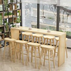 a table with stools in front of it and plants on the shelves behind it