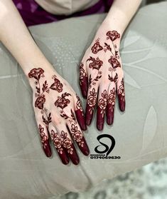 a woman's hands with hennap and flowers painted on her hand, sitting on a cushion