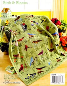 a green blanket with birds on it is sitting on the floor next to potted plants